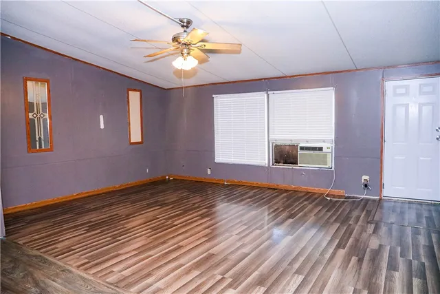 a view of an empty room with window and wooden floor