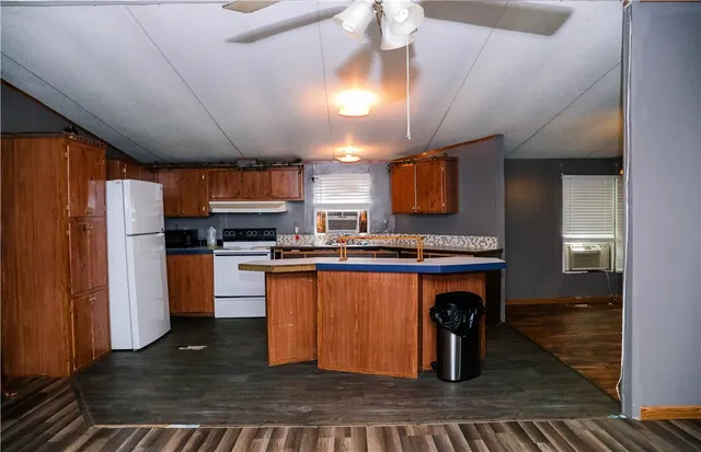 a kitchen with stainless steel appliances granite countertop a refrigerator a sink dishwasher a stove and a dining table with wooden floor