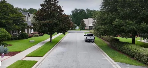 an aerial view of a tennis ground and a cars park side of the road