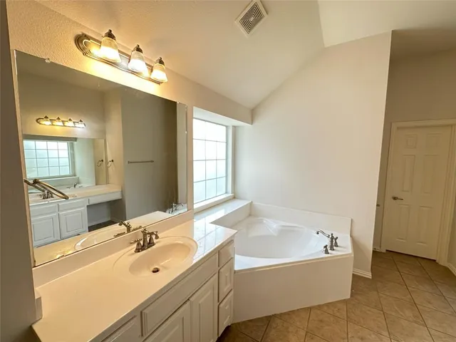 a bathroom with a tub sink and mirror