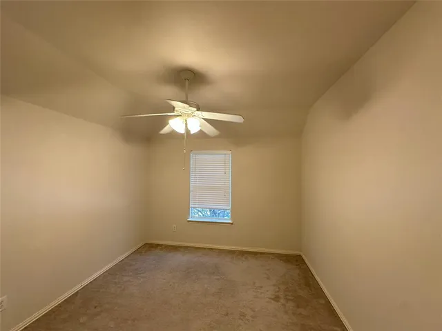 an empty room with a chandelier fan and windows