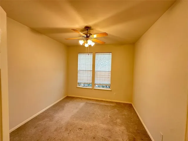 an empty room with windows and chandelier fan