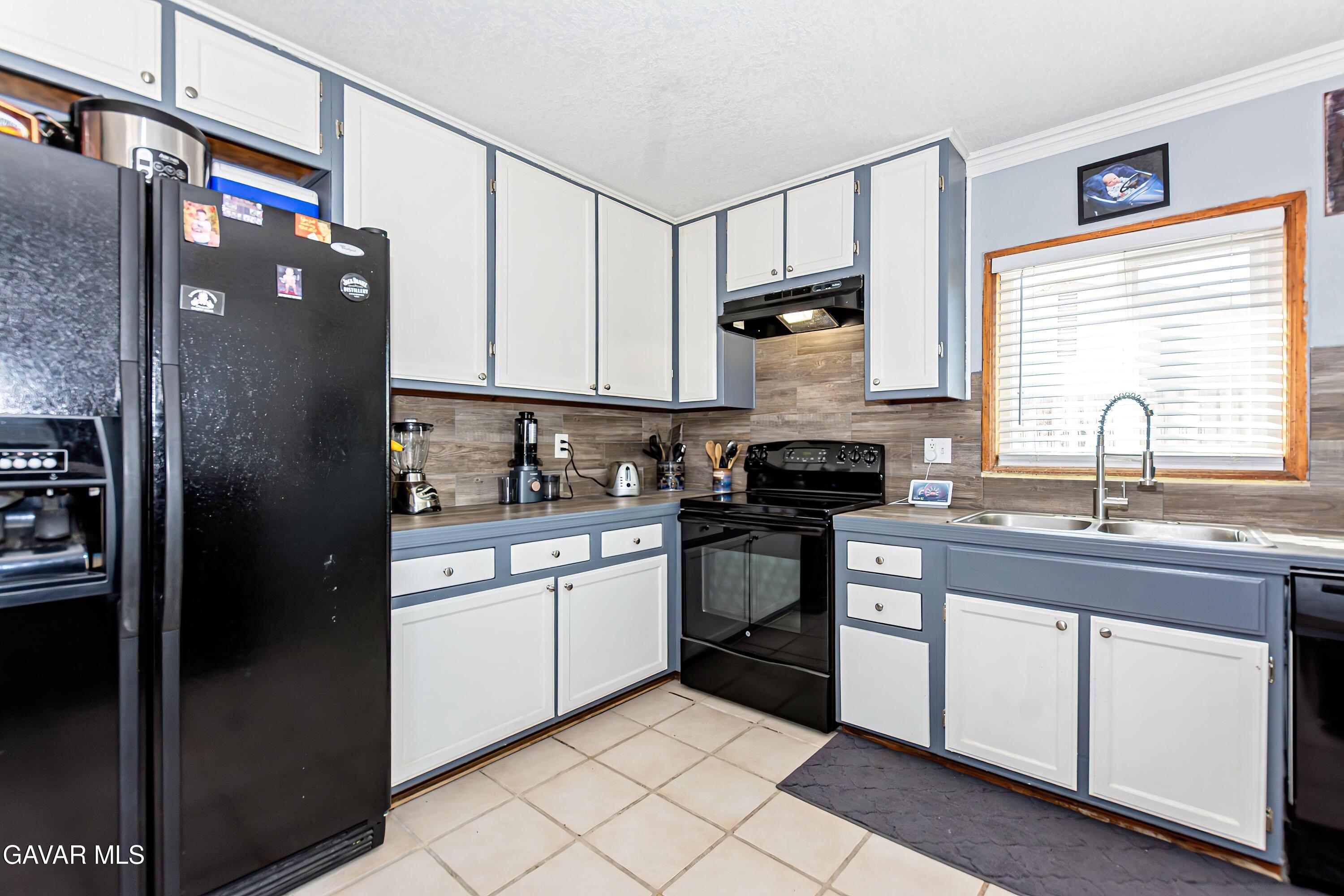 42933 Alexo Drive Lancaster, CA 93536 - Photo 13 of 32 a kitchen with stainless steel appliances granite countertop a refrigerator a sink and white cabinets