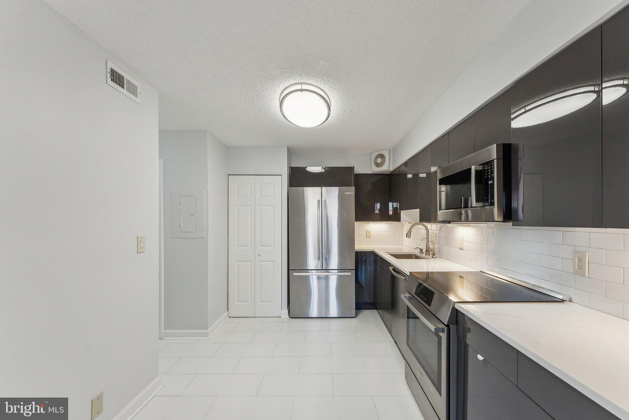 1077 30th Street Northwest, Unit 705 Washington, DC 20007 - Photo 12 of 31 a kitchen with stainless steel appliances granite countertop a sink and a refrigerator