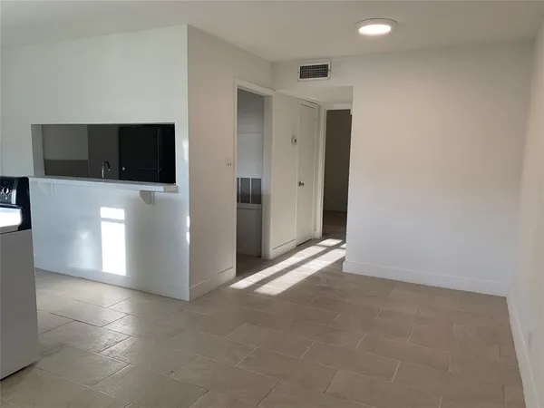 a view of an empty room with a window and a kitchen