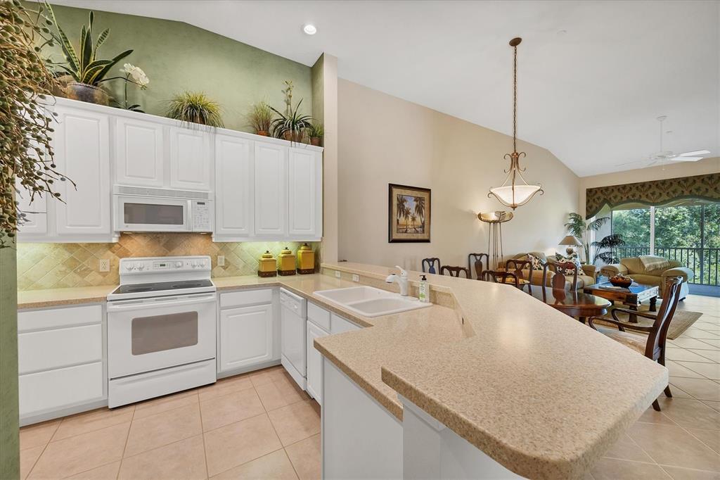7115 Boca Grove Place, Unit 204 Lakewood Ranch, FL 34202 - Photo 11 of 40 a kitchen with a sink a stove and chairs