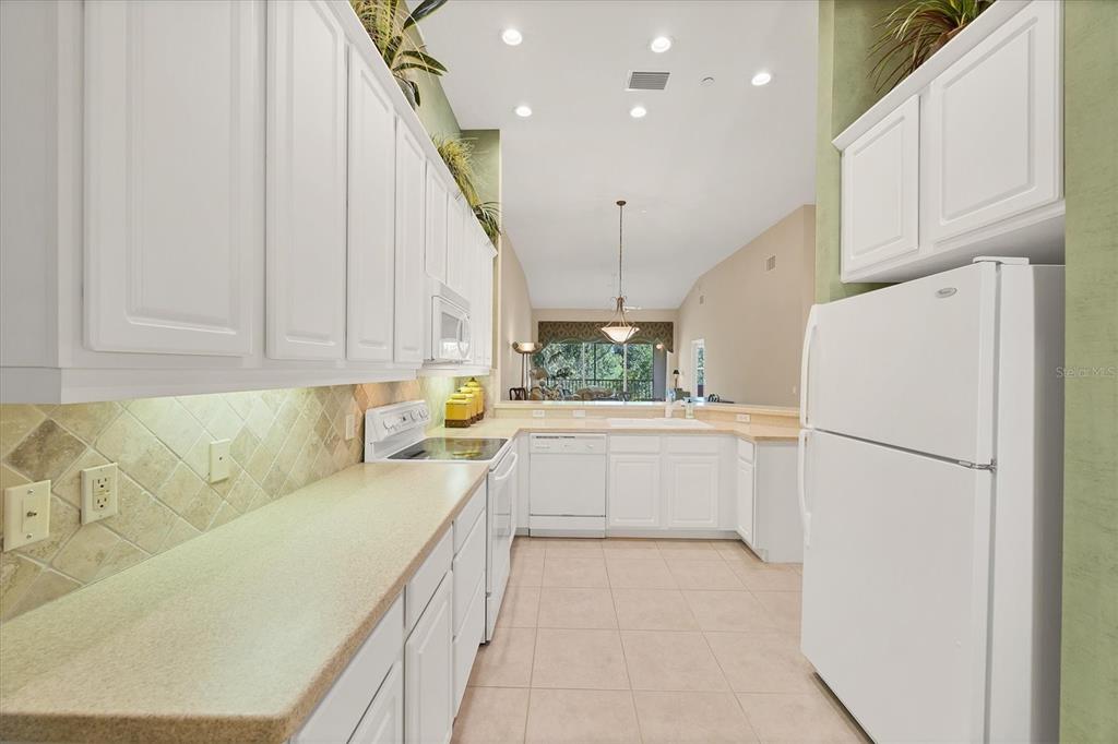7115 Boca Grove Place, Unit 204 Lakewood Ranch, FL 34202 - Photo 12 of 40 a kitchen with a refrigerator a sink and white cabinets