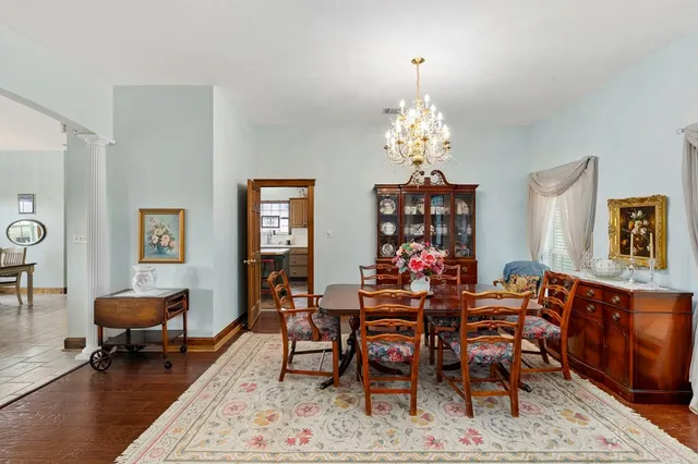 a dining room with wooden floor a chandelier a wooden table and chairs