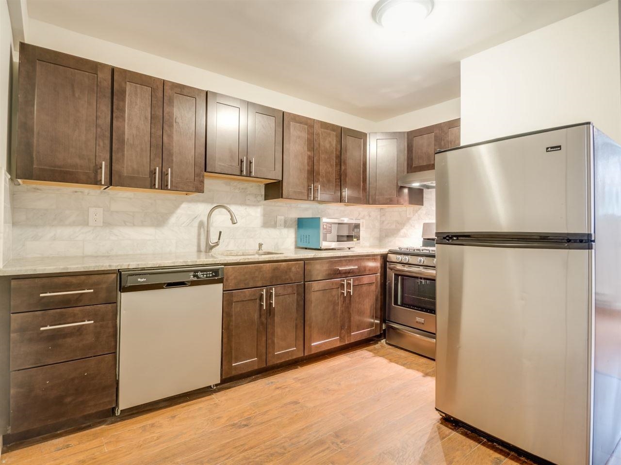 a kitchen with granite countertop a refrigerator sink stove and cabinets