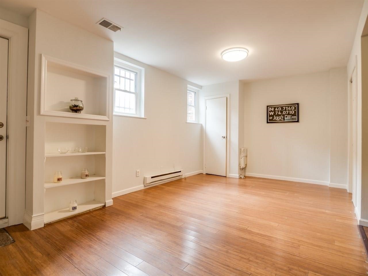 226 Christopher Columbus Drive, Unit 1 Jersey City, NJ 07302 - Photo 3 of 8 an empty room with wooden floor & closet area