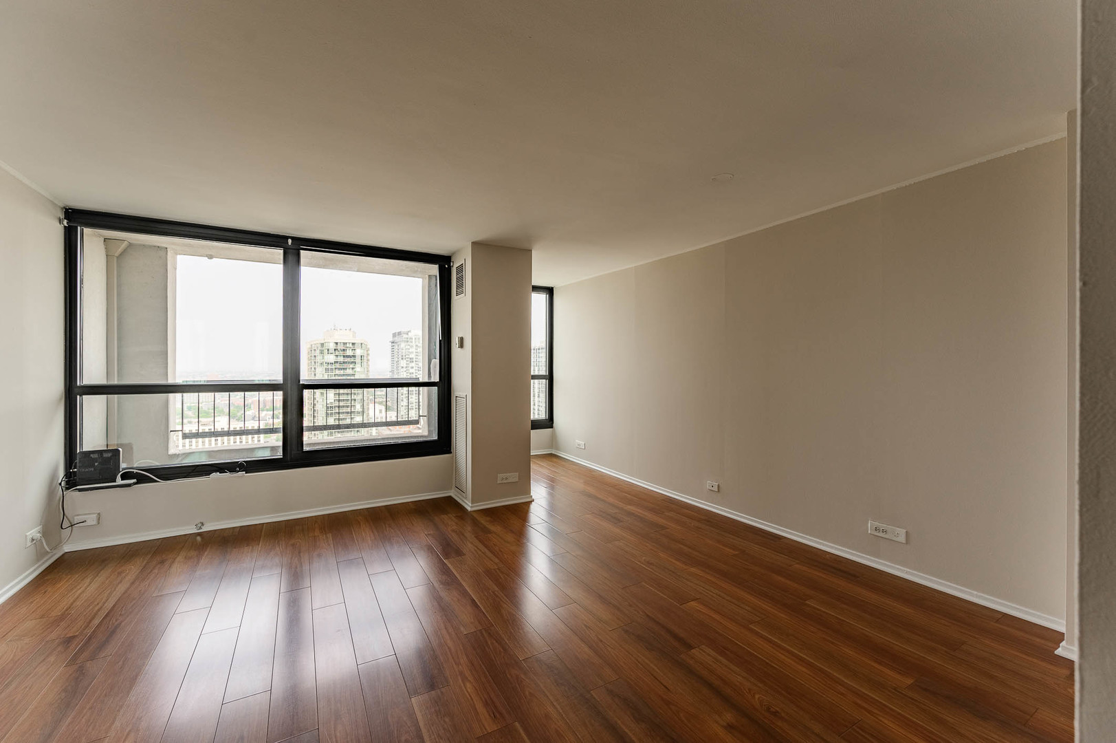 1030 North State Street, Unit 29M Chicago, IL 60610 - Photo 5 of 11 an empty room with wooden floor and windows