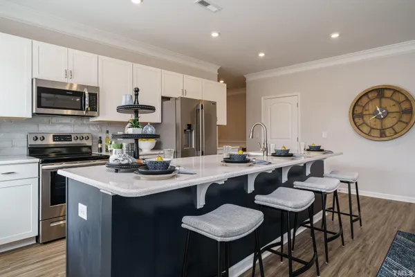 a kitchen with stainless steel appliances granite countertop a sink a stove a refrigerator a dining table and chairs