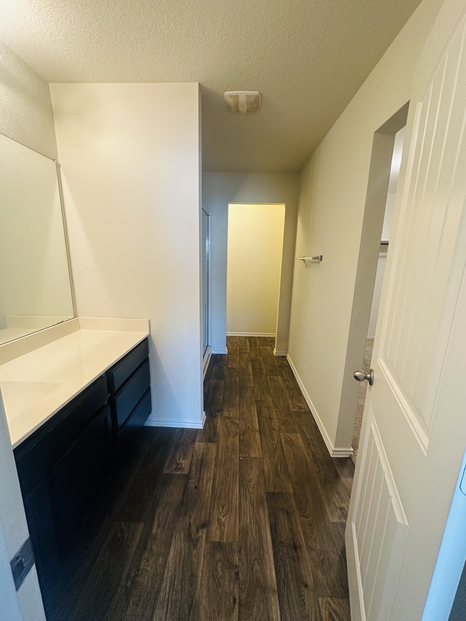 14915 Talus Road Manor, TX 78653 - Photo 13 of 22 Rich wood-look flooring anchors this modern bathroom with its clean-lined vanity and neutral finishes.