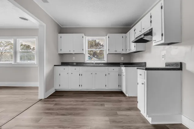 a kitchen with granite countertop a sink cabinets and wooden floor