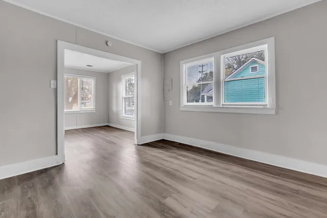 an empty room with wooden floor and windows