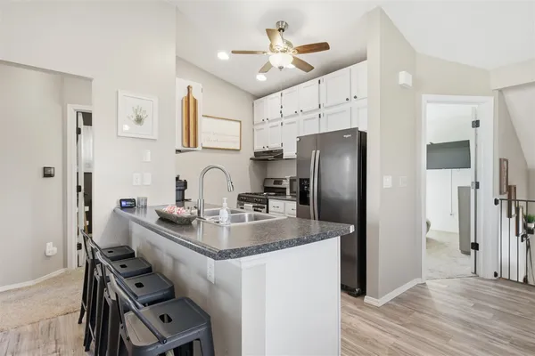 a kitchen with stainless steel appliances granite countertop a refrigerator a sink dishwasher a stove and a refrigerator with wooden floor