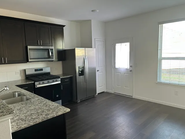 a kitchen with granite countertop wooden cabinets a refrigerator and a stove