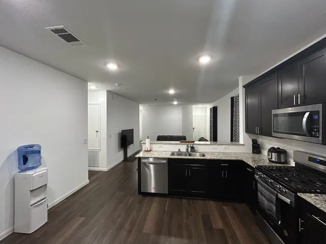 a kitchen with kitchen island granite countertop a sink stainless steel appliances and cabinets