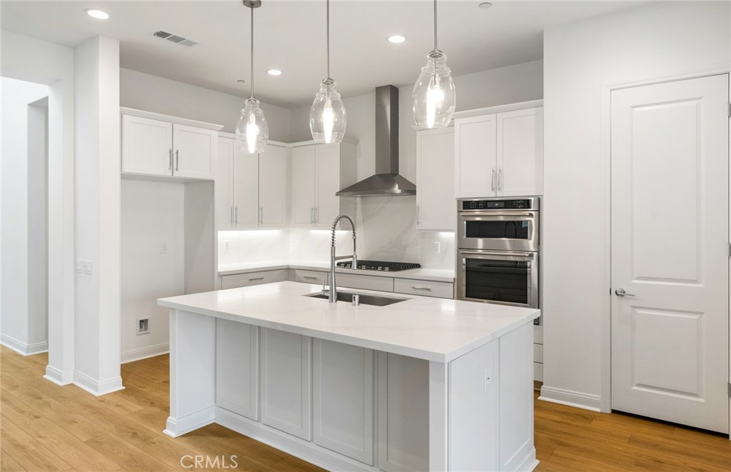 743 Corkscrew Road Rancho Mission Viejo, CA 92694 - Photo 8 of 35 a kitchen with stainless steel appliances a stove a sink a refrigerator and white cabinets with wooden floor
