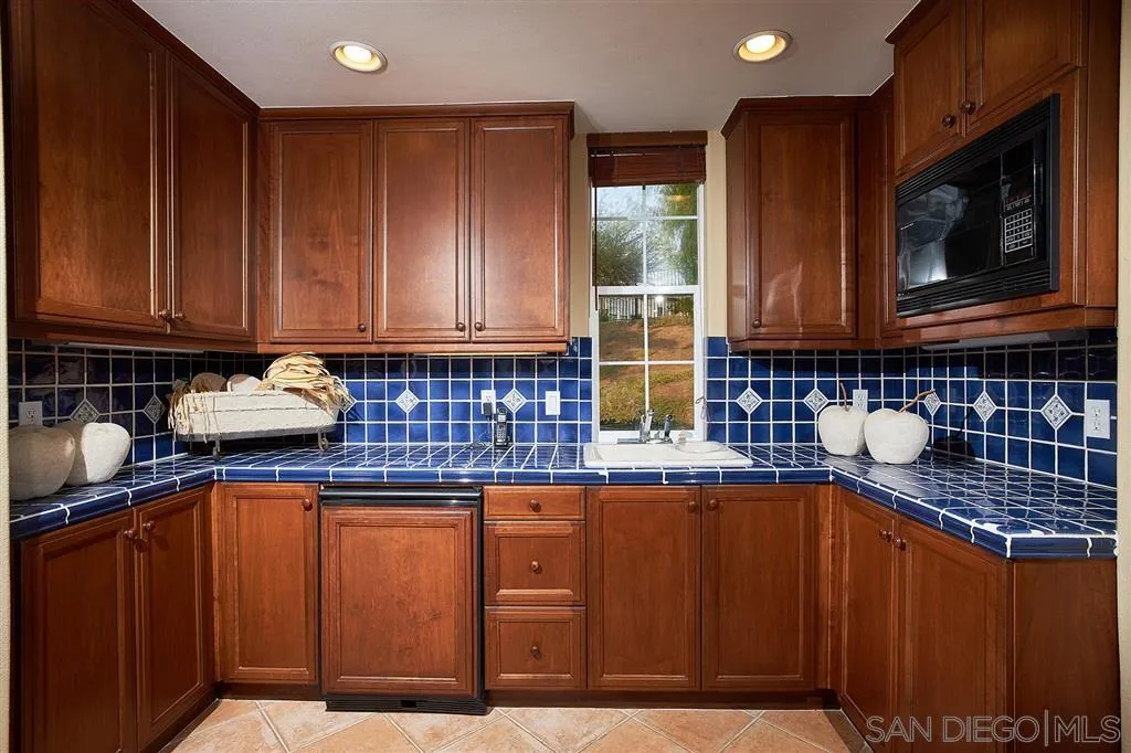 13625 Ash Hollow Crossing Road Poway, CA 92064 - Photo 18 of 25 a kitchen with wooden cabinets a sink and a microwave