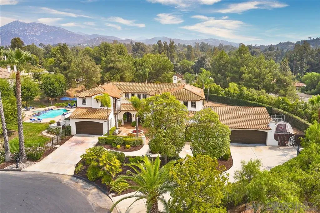 13625 Ash Hollow Crossing Road Poway, CA 92064 - Photo 22 of 25 a view of a white house with a yard and table and chairs under an umbrella