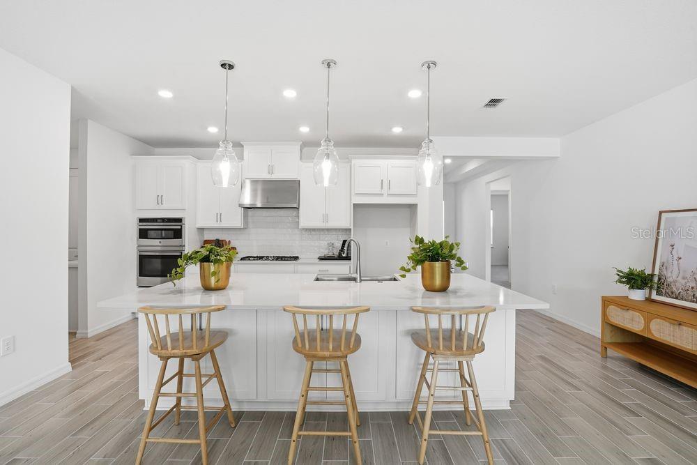 14242 Sawmill Street Parrish, FL 34219 - Photo 2 of 41 a kitchen with stainless steel appliances kitchen island granite countertop a dining table chairs and white cabinets