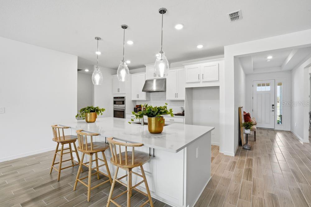14242 Sawmill Street Parrish, FL 34219 - Photo 4 of 41 a kitchen with stainless steel appliances kitchen island granite countertop a table and chairs in it