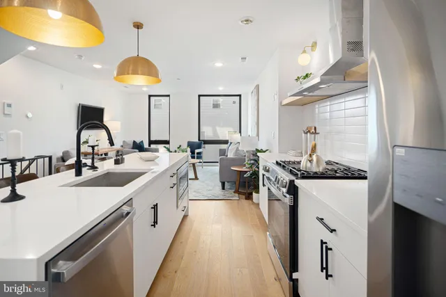 a large kitchen with stainless steel appliances a sink a stove and a dining table