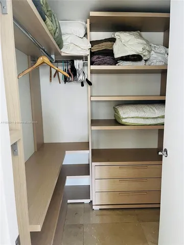 a view of walk in closet with clothes and shoes