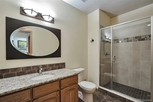 a bathroom with a granite countertop toilet sink and mirror