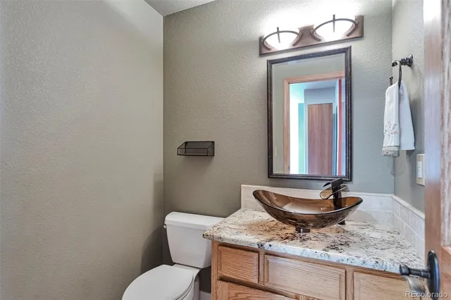 a bathroom with a granite countertop sink a toilet and mirror