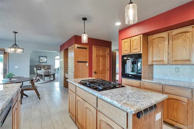 a kitchen with stainless steel appliances granite countertop a stove a sink dishwasher and white cabinets with wooden floor