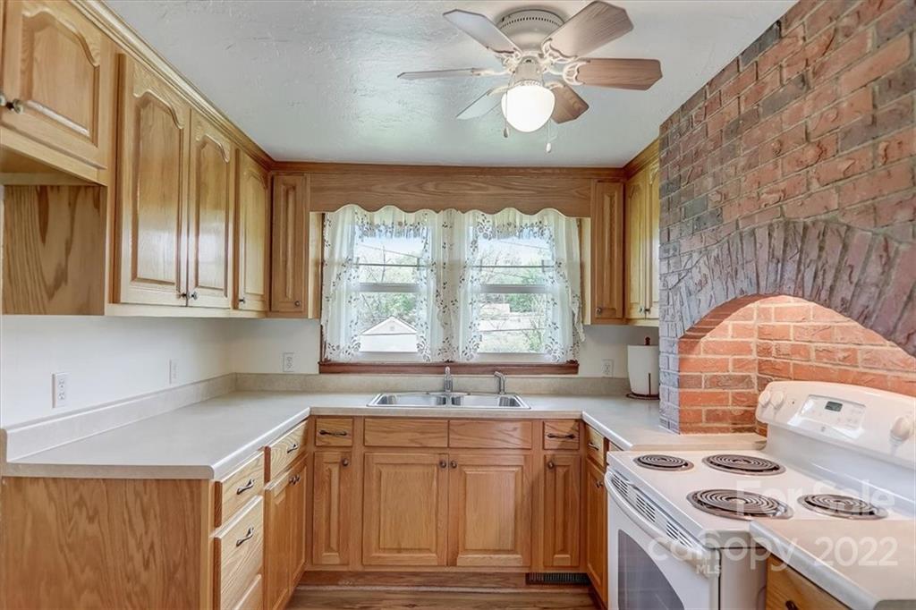 115 Substation Road Canton, NC 28716 - Photo 9 of 41 a kitchen with stainless steel appliances granite countertop a stove a sink and a granite counter tops with white cabinets next to a window