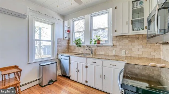 a kitchen with granite countertop a sink cabinets stainless steel appliances and a window