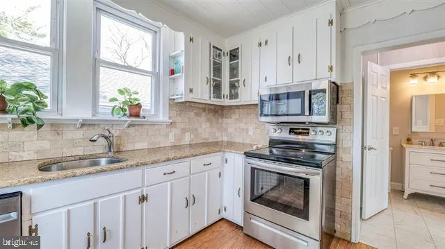 a kitchen with granite countertop white cabinets stainless steel appliances and sink