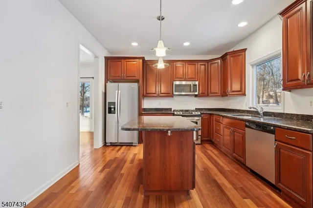 a kitchen with stainless steel appliances granite countertop wooden floors wooden cabinets and sink