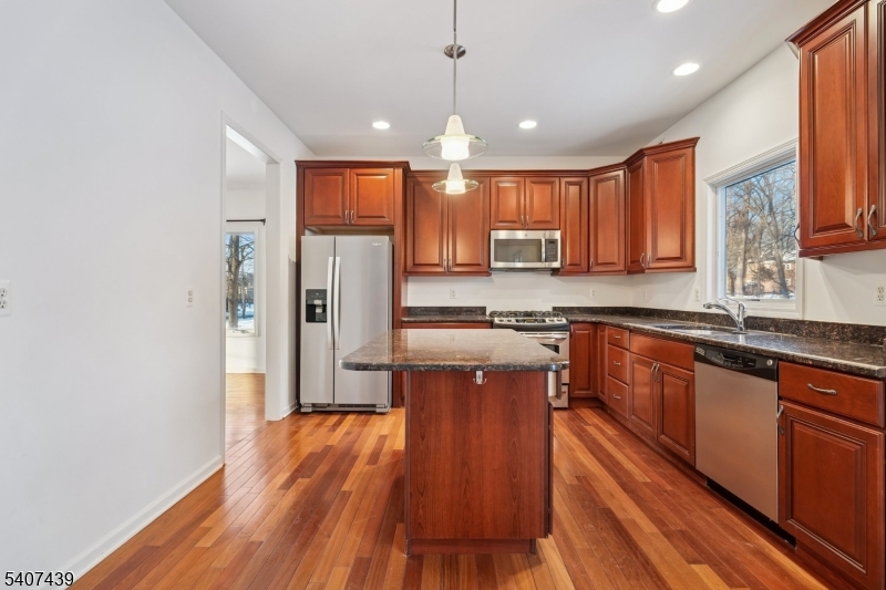 282 South Street, Unit B New Providence, NJ 07974 - Photo 10 of 28 a kitchen with stainless steel appliances granite countertop wooden floors wooden cabinets and sink