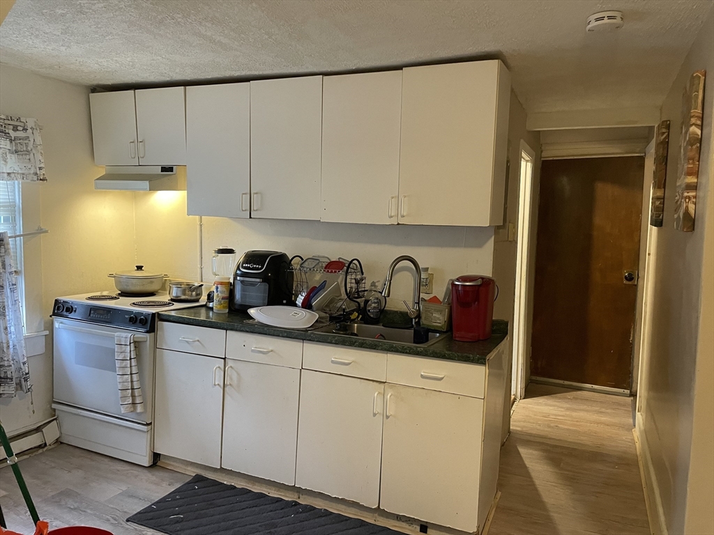 61-63 Pomona Street Springfield, MA 01108 - Photo 5 of 10 a kitchen with stainless steel appliances a sink a stove and white cabinets