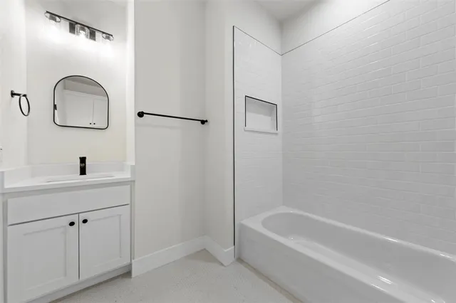a bathroom with a tub a sink and mirror