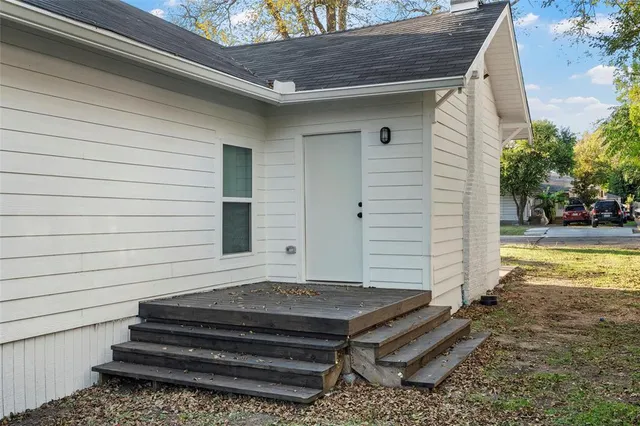 a view of a backyard with a chair and floor to ceiling window and potted plants