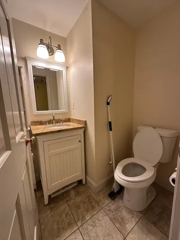a bathroom with a granite countertop toilet and a sink