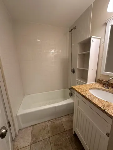 a bathroom with a granite countertop sink a toilet and bathtub