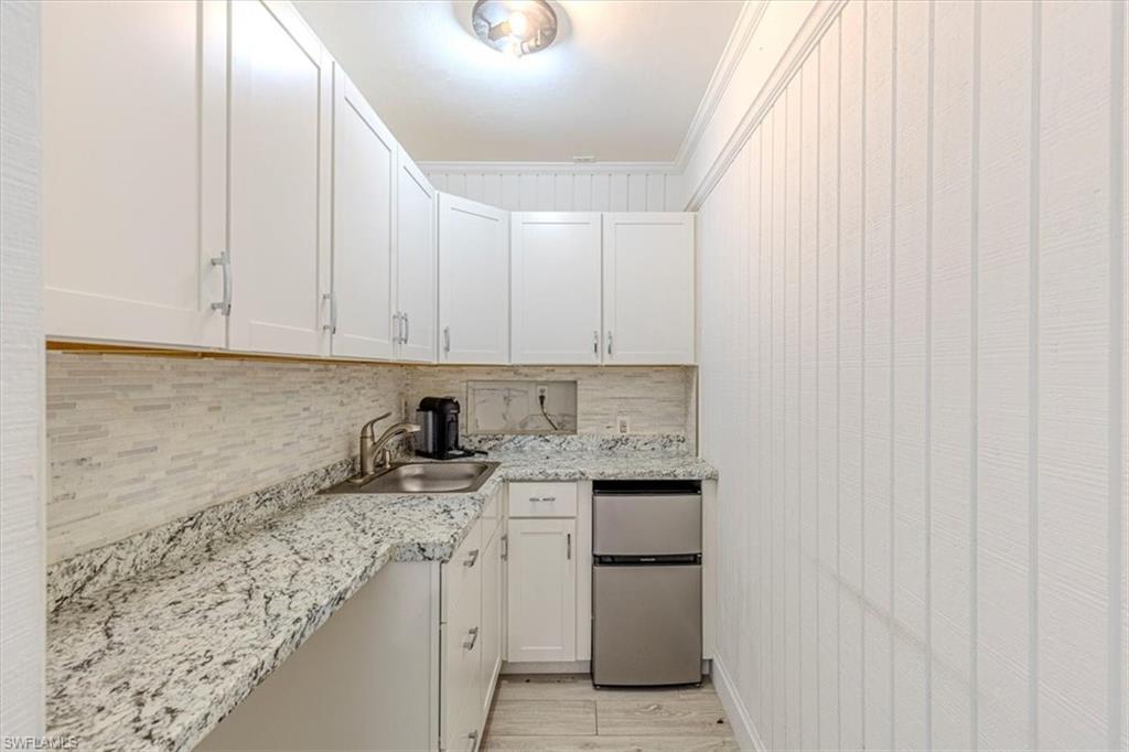 3618 Cottage Club Lane Naples, FL 34105 - Photo 11 of 26 a kitchen with granite countertop white cabinets and white appliances