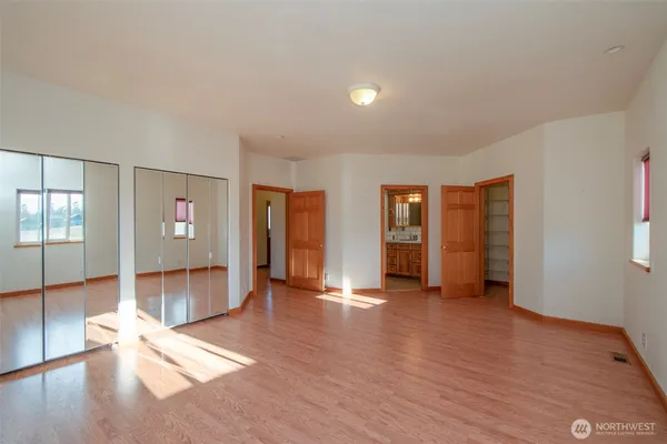 a view of an empty room with window and wooden floor