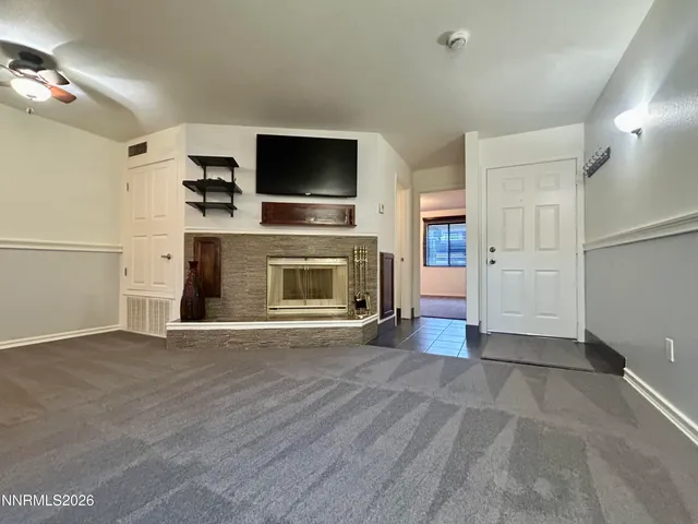 a view of a livingroom with a fireplace a flat screen tv and staircase