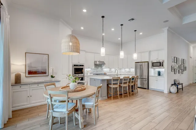a kitchen with a dining table chairs wooden floor appliances and cabinets