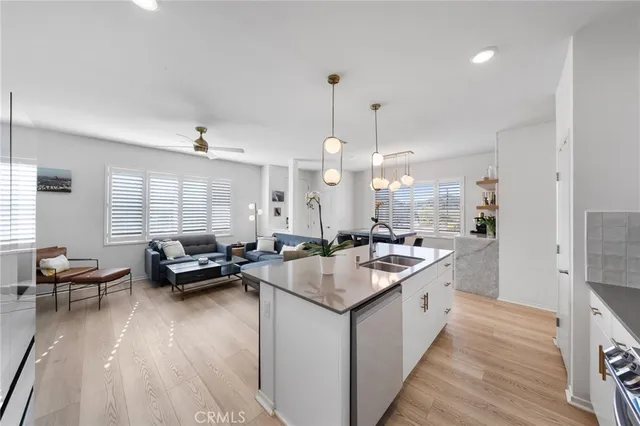 a kitchen with stainless steel appliances kitchen island granite countertop a stove a sink a refrigerator and white cabinets with wooden floor