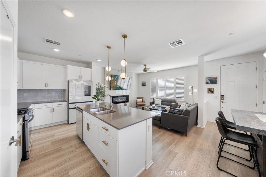 303 Sweet Place Fallbrook, CA 92028 - Photo 10 of 59 a kitchen with stainless steel appliances kitchen island granite countertop a stove a sink a refrigerator and white cabinets with wooden floor