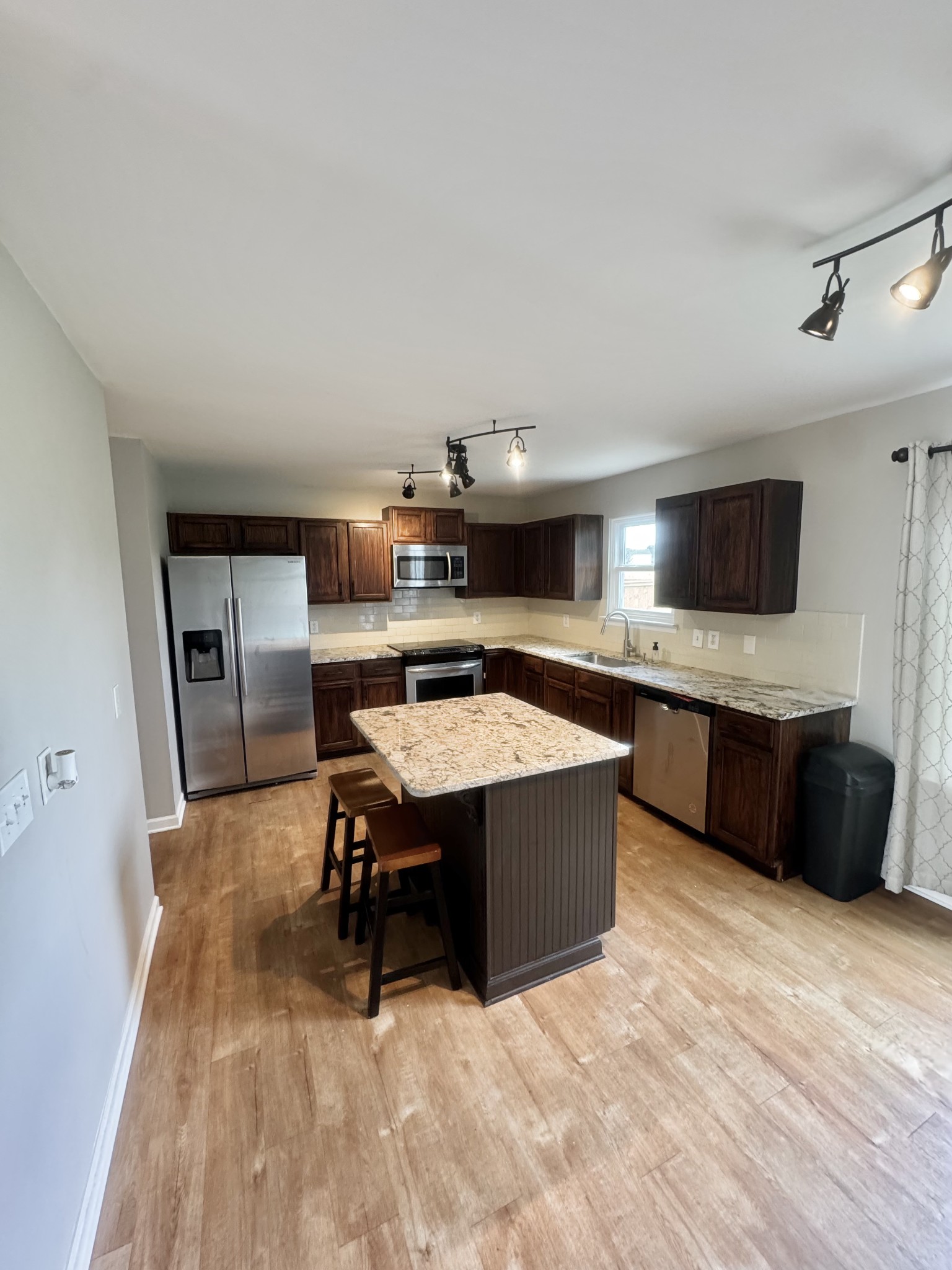 4017 Cadence Drive Spring Hill, TN 37174 - Photo 7 of 38 a living room with stainless steel appliances kitchen island granite countertop a sink dishwasher a stove a microwave oven and a dining table with wooden floor