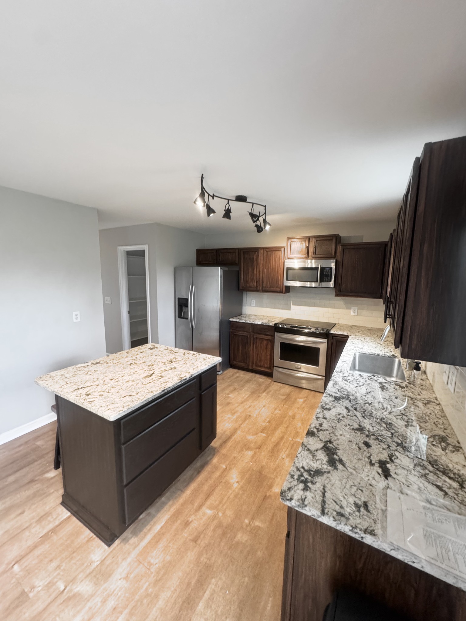 4017 Cadence Drive Spring Hill, TN 37174 - Photo 9 of 38 a living room with stainless steel appliances kitchen island granite countertop a table chairs in it and wooden floors